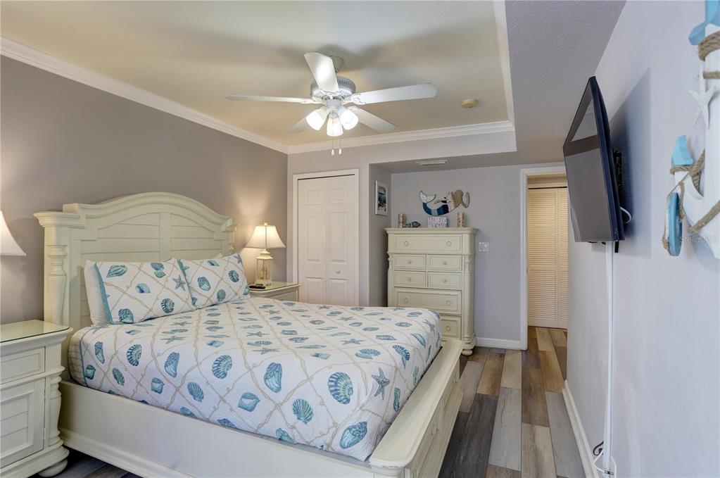 A bedroom features a queen bed with seashell bedding, a white dresser, and wood-look flooring — 19417 GULF BOULEVARD UNIT A202, INDIAN SHORES, FL