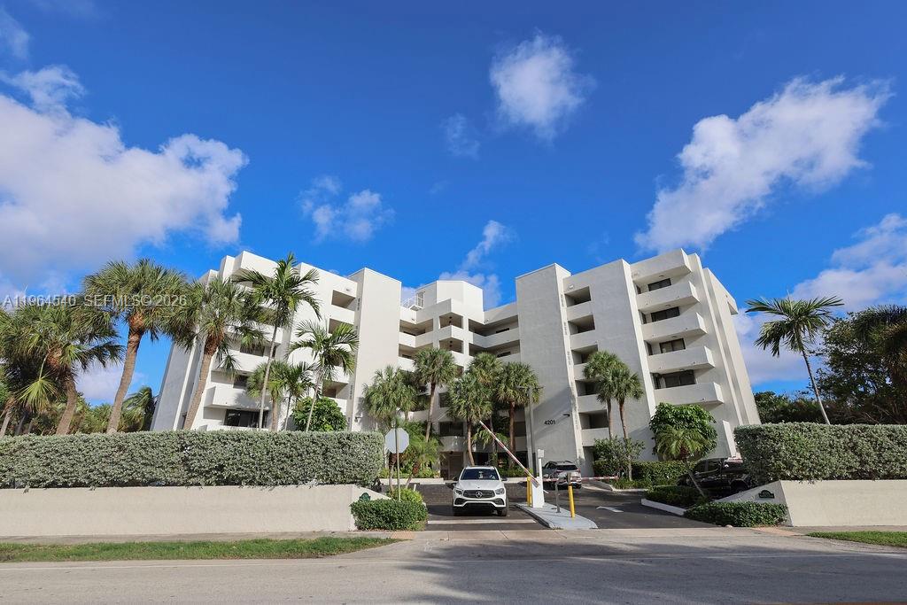 A multi-story white apartment building stands behind a gated entrance with palm trees — 4201 N Ocean Dr # 304, Hollywood FL 33019, HOLLYWOOD, FL