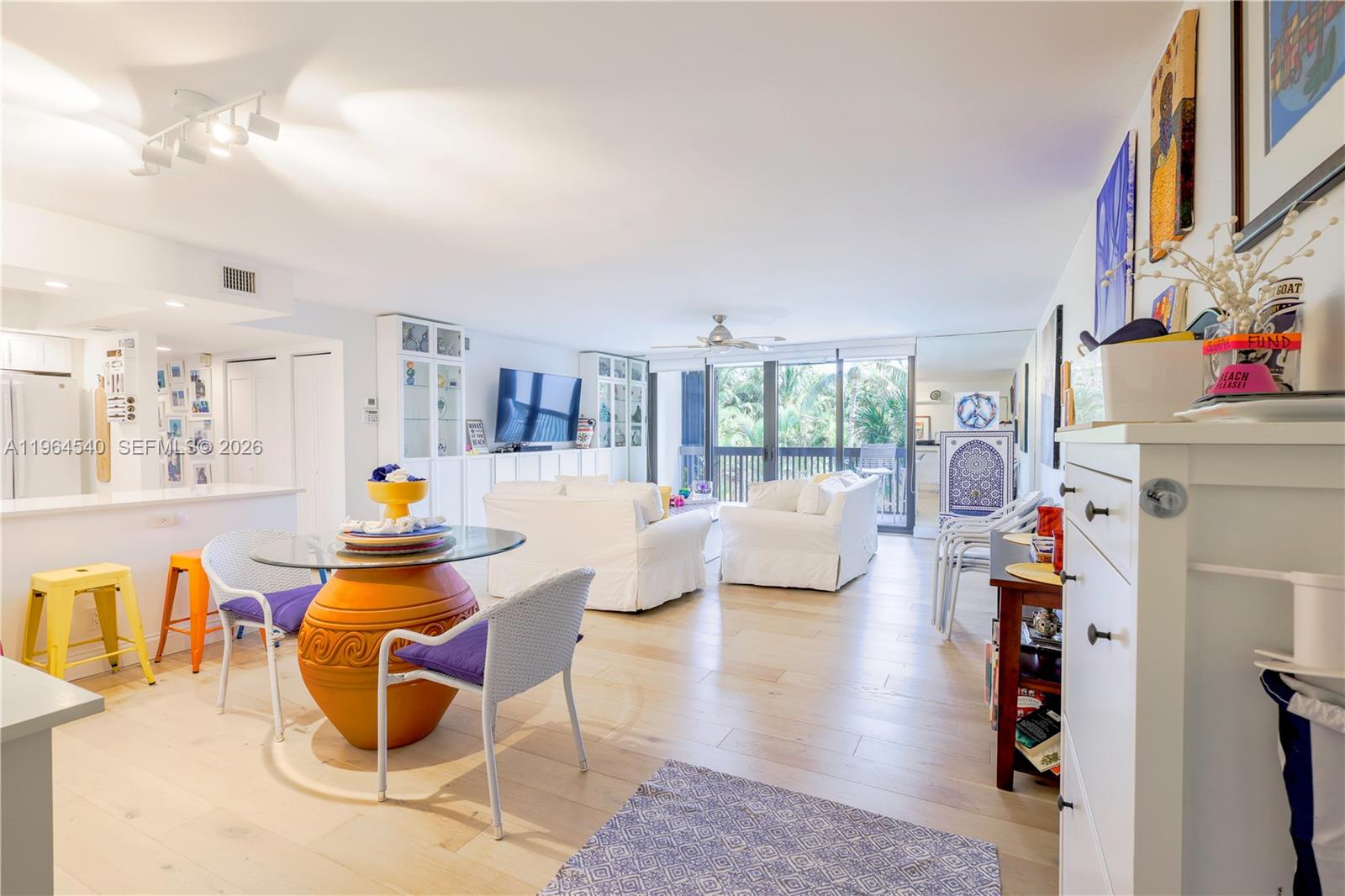 A bright living and dining area with light wood floors, white furniture, and glass doors — 4201 N Ocean Dr # 304, Hollywood FL 33019, HOLLYWOOD, FL