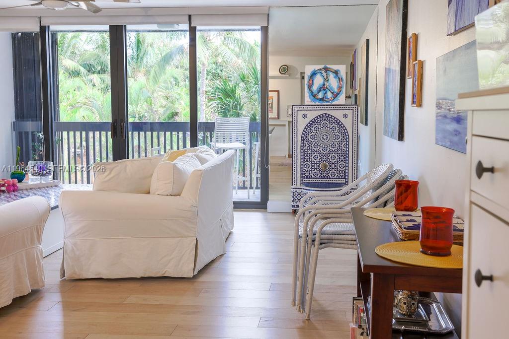 A living room features a white sofa, light wood floors, and a balcony with palm trees — 4201 N Ocean Dr # 304, Hollywood FL 33019, HOLLYWOOD, FL