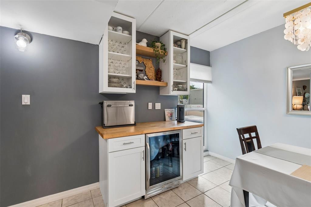 A dining area features a white cabinet wet bar with a wood countertop and shelving — 2424 W TAMPA BAY BOULEVARD UNIT I204, TAMPA, FL