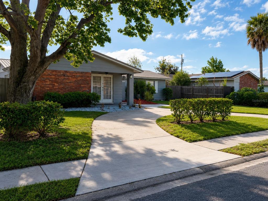 A single-story house with a brick and gray siding exterior, a curved driveway, and landscaping — 6518 VOLTAIRE DRIVE, ORLANDO, FL