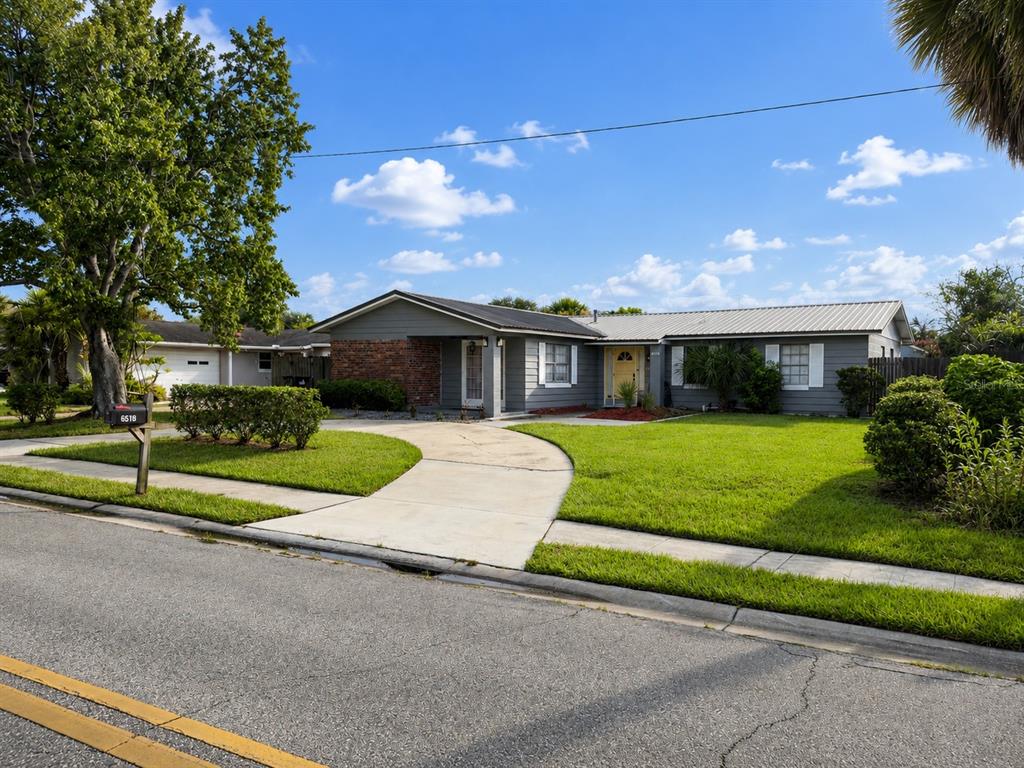 A single-story gray house with a brick accent wall and a curved concrete driveway — 6518 VOLTAIRE DRIVE, ORLANDO, FL