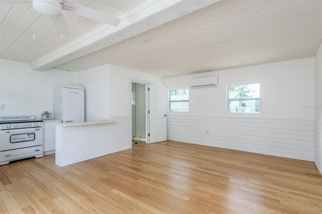 A kitchen and living area with white shiplap walls, wood flooring, and a ceiling fan — 1115 PENNSYLVANIA AVENUE, PALM HARBOR, FL