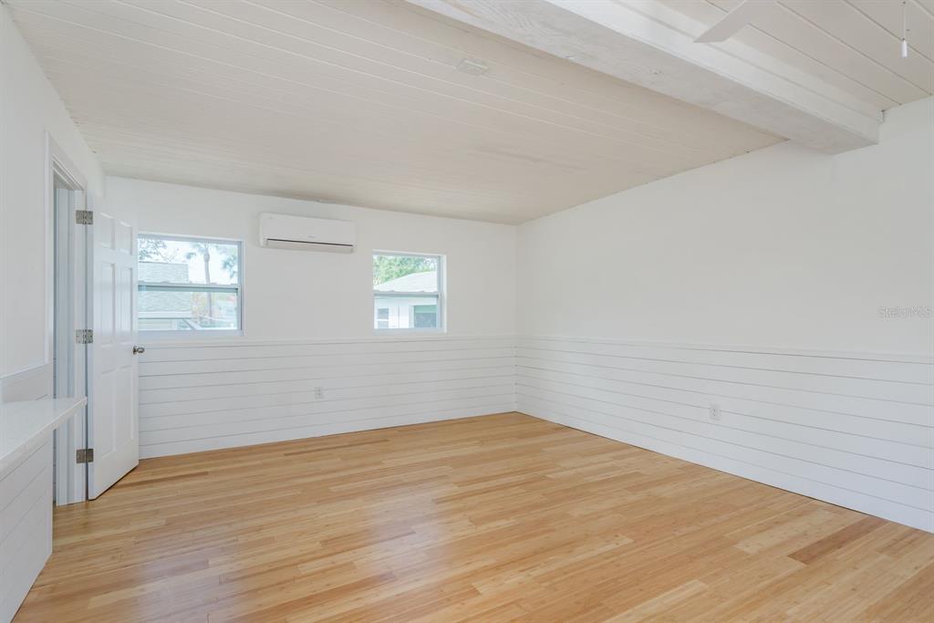 An empty room features white shiplap walls, a wood-plank ceiling, and light-colored hardwood flooring — 1115 PENNSYLVANIA AVENUE, PALM HARBOR, FL