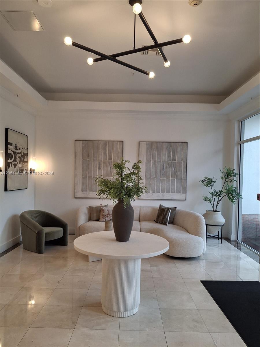 A modern lobby features a curved sofa, a round pedestal table, and a geometric chandelier — 9021 SW 94th St, Miami FL 33176, MIAMI, FL