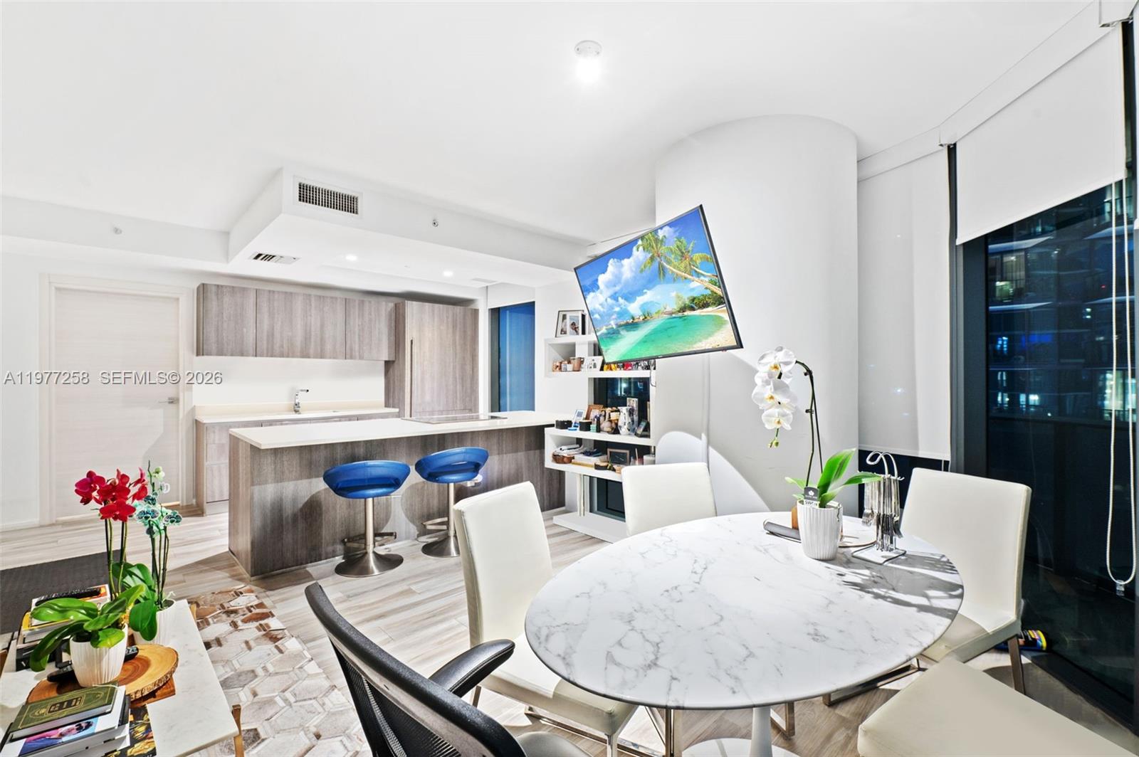 A modern kitchen with wood cabinetry and a dining area featuring a marble table — 801 S Miami Ave # 2705, Miami FL 33130, MIAMI, FL