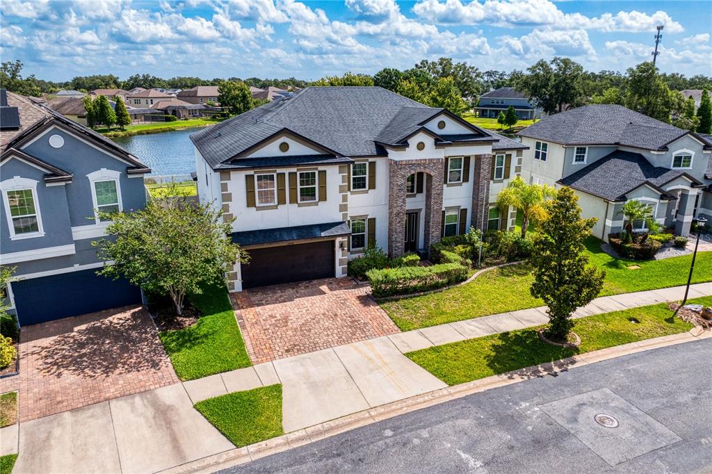 An aerial view of a two-story suburban house with a brick driveway and lake view — 10506 ALCON BLUE DRIVE, RIVERVIEW, FL