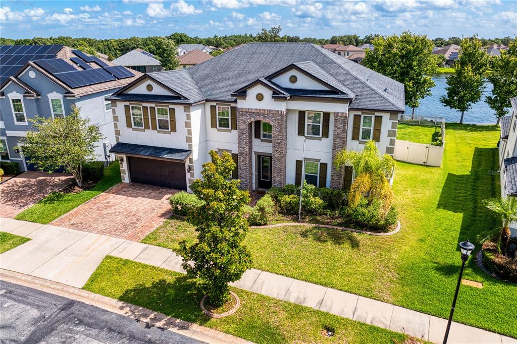 An aerial view of a two-story suburban house with a stone facade and brick driveway — 10506 ALCON BLUE DRIVE, RIVERVIEW, FL