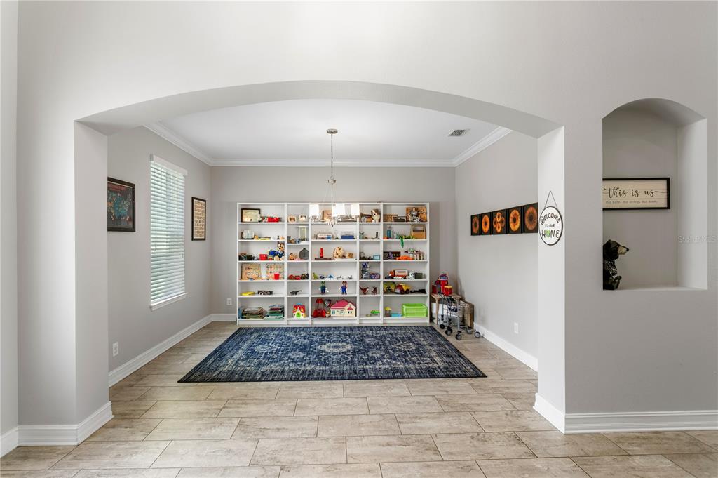 A playroom with light tile floors, a large blue rug, and white shelving units — 10506 ALCON BLUE DRIVE, RIVERVIEW, FL