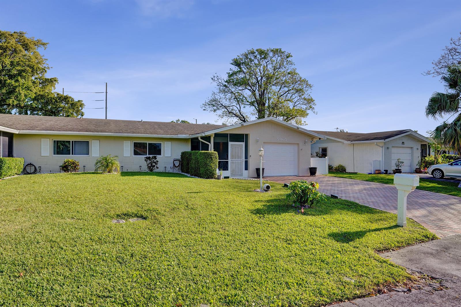 A single-story house with a beige exterior, a white garage door, and a paved driveway — 5965 Los Alamos Lane, Delray Beach FL 33484, DELRAY BEACH, FL