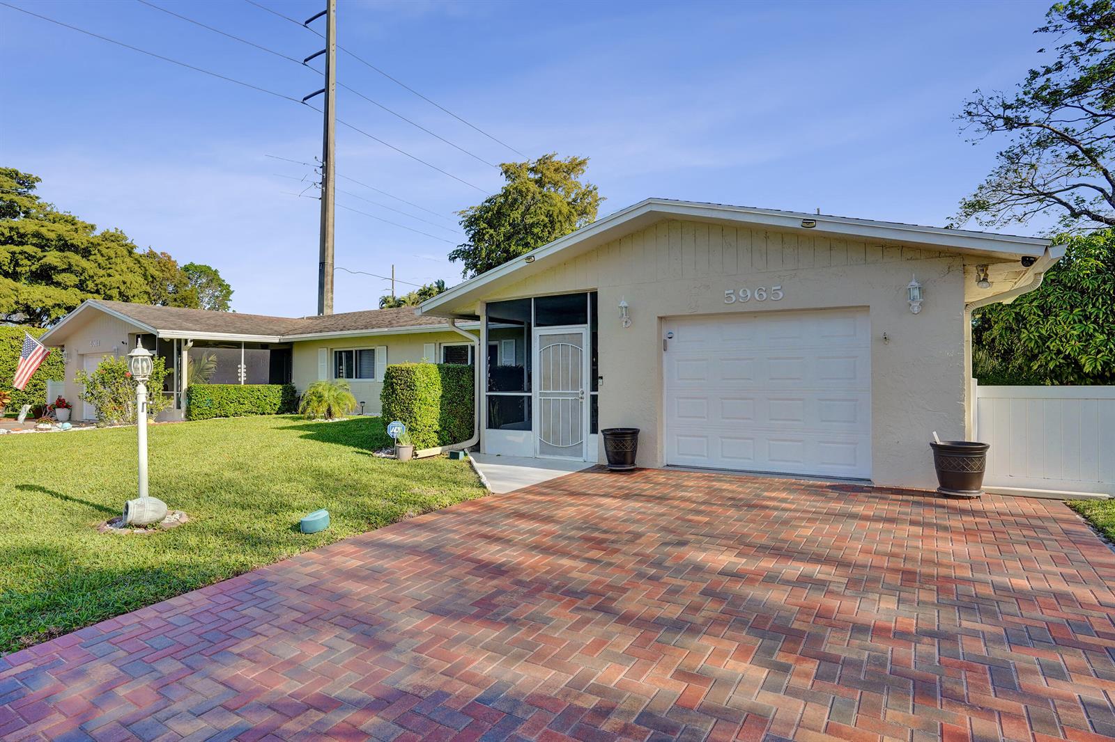 A single-story house with a brick driveway, a white garage door, and a screened entryway — 5965 Los Alamos Lane, Delray Beach FL 33484, DELRAY BEACH, FL