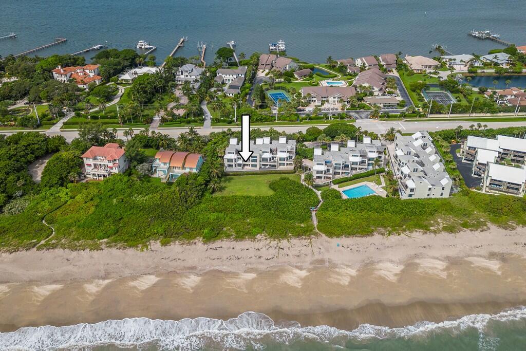 An aerial view shows a multi-story residential building on a sandy beach near the ocean — 2051 NE Ocean Boulevard # C13, Stuart FL 34996, STUART, FL