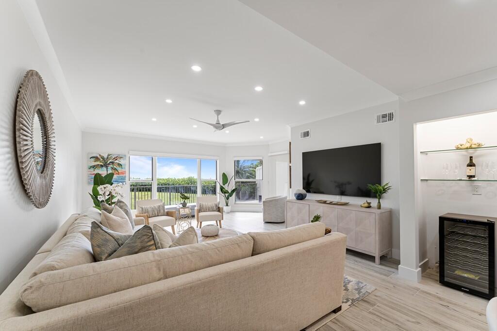 A bright living room features a large sectional sofa, a television, and a wine cooler — 2051 NE Ocean Boulevard # C13, Stuart FL 34996, STUART, FL