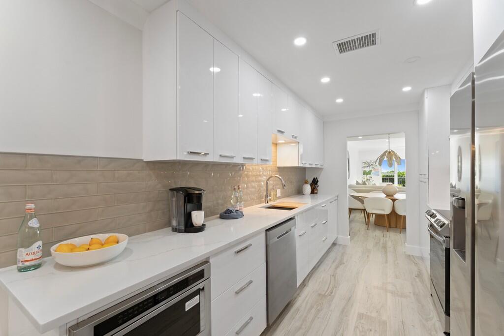 A modern kitchen features white cabinets, stainless steel appliances, and light-colored tile flooring — 2051 NE Ocean Boulevard # C13, Stuart FL 34996, STUART, FL
