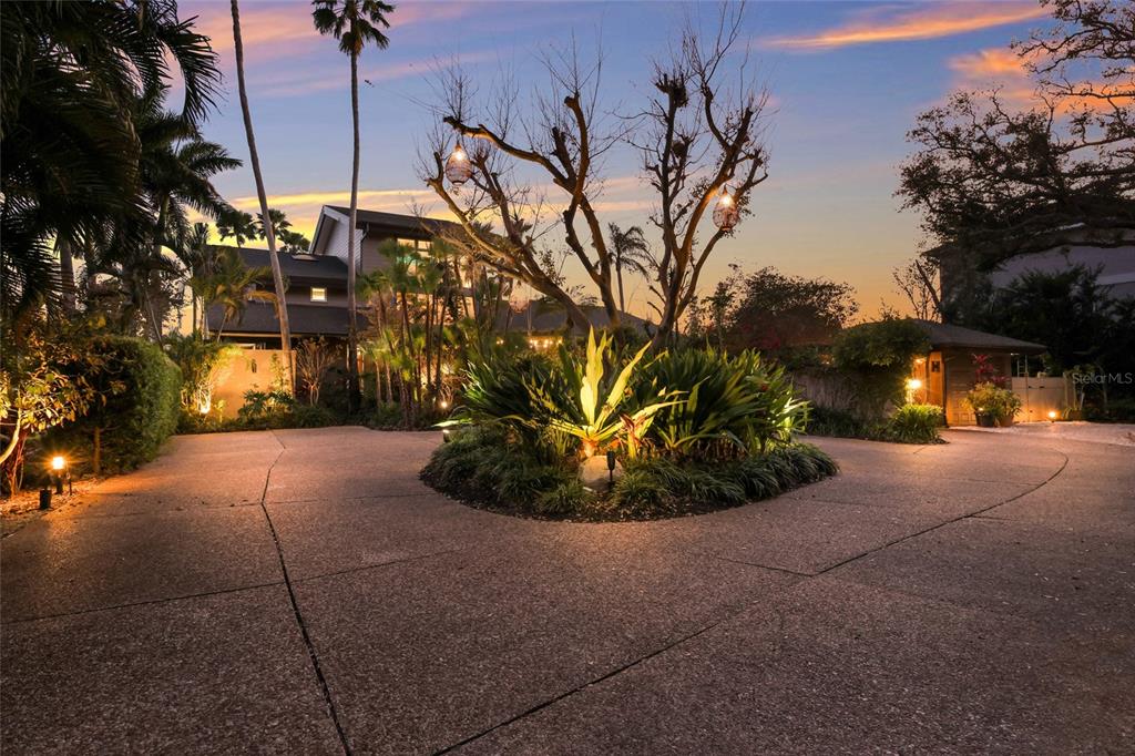 A circular driveway surrounds a landscaped island with tropical plants in front of a house — 608 87TH STREET COURT NW, BRADENTON, FL