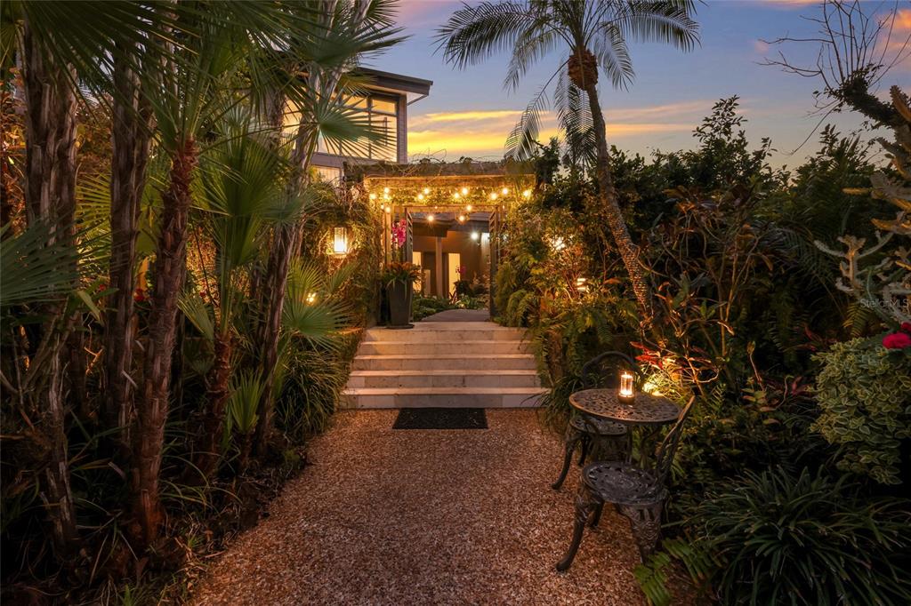 A stone path leads to a set of stairs under a string-lit pergola at dusk — 608 87TH STREET COURT NW, BRADENTON, FL