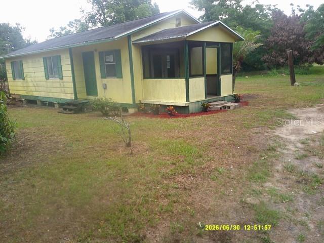 A yellow house with a screened-in front porch sits on a grassy lot with trees — 6229 TERRELL ROAD, MOUNT DORA, FL