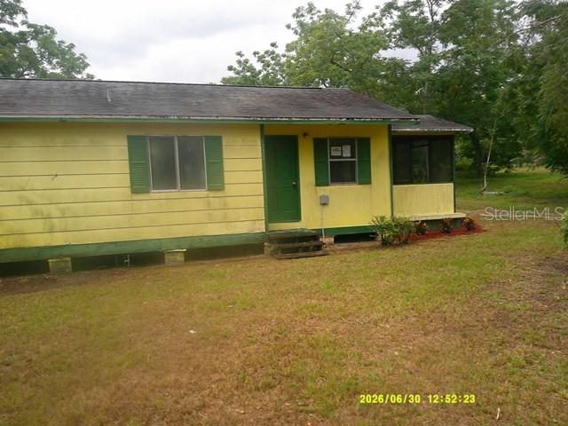A yellow house with a screened-in porch and wooden decking stands in a grassy yard — 6229 TERRELL ROAD, MOUNT DORA, FL