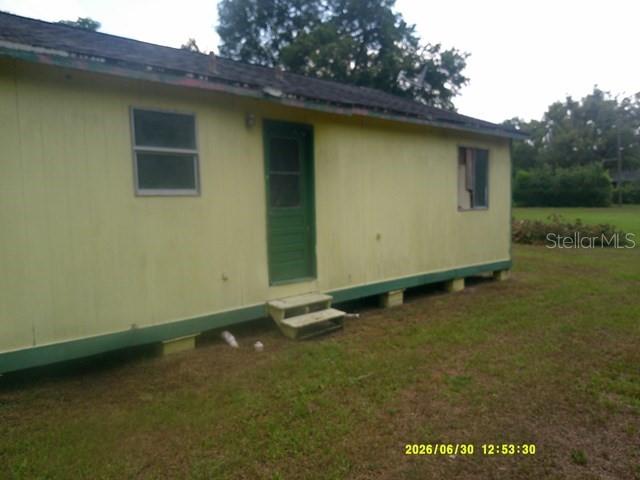 A yellow, single-story house with green shutters sits on a foundation above the ground — 6229 TERRELL ROAD, MOUNT DORA, FL