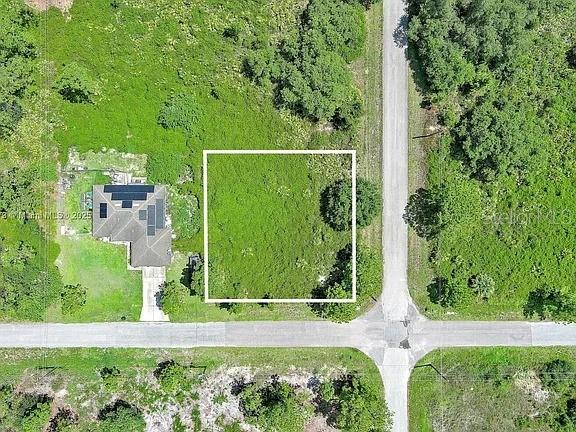 An aerial view shows a vacant, rectangular lot adjacent to a house and paved roads — 3100 E 13TH STREET, LEHIGH ACRES, FL