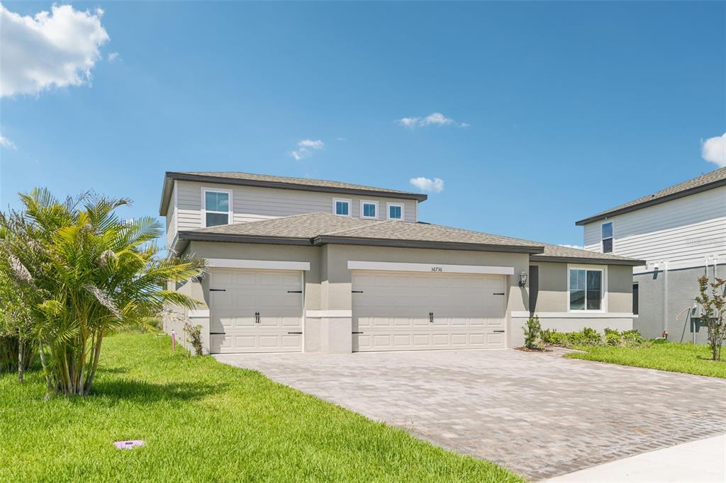 A two-story suburban house with a three-car garage and a paved driveway — 36736 MELSTONE WAY, ZEPHYRHILLS, FL