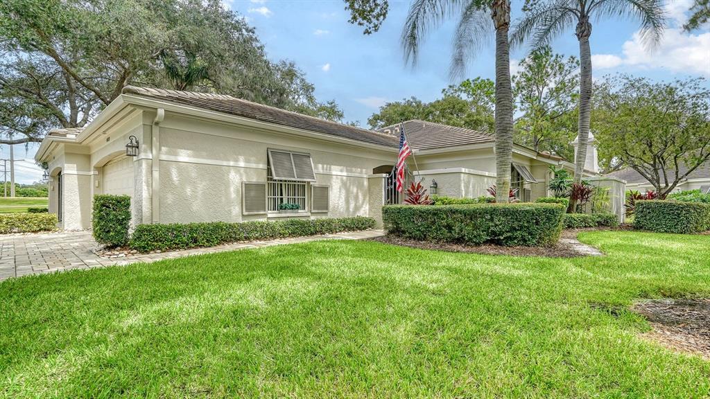 A single-story house with a beige stucco exterior, a tiled roof, and a manicured lawn — 4419 OAKLEY GREENE UNIT 19, SARASOTA, FL