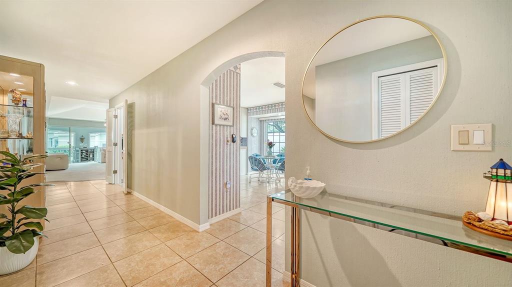 A tiled hallway leads through an arched doorway to a dining area with a mirror — 4419 OAKLEY GREENE UNIT 19, SARASOTA, FL