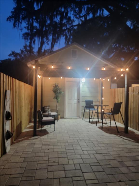 A paved patio area features a pergola with string lights, outdoor seating, and a wooden fence — 5651 ORANGE GROVE AVENUE, NEW PORT RICHEY, FL
