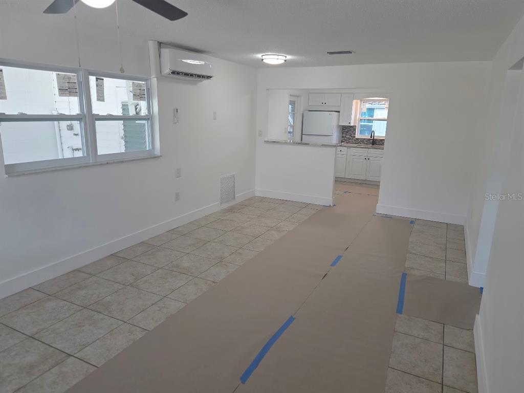 An interior view shows a living area with tile floors and a pass-through kitchen — 4994 JONQUIL PLACE N UNIT 278, PINELLAS PARK, FL