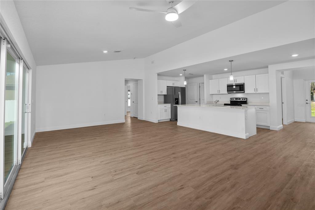 An open-concept living area features light wood-look flooring, white walls, and a modern kitchen — 4462 AMARI ROAD, NORTH PORT, FL