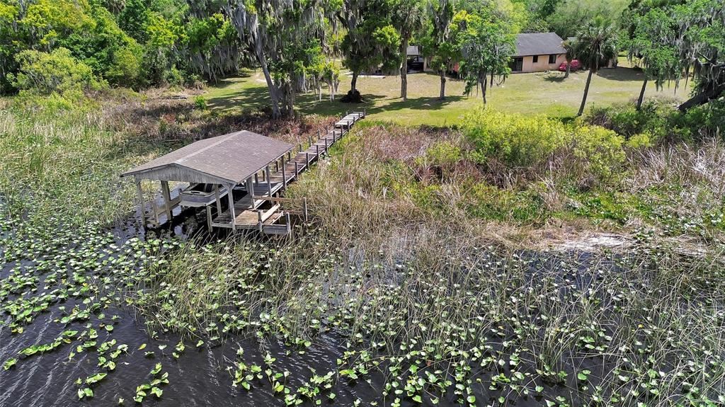 An aerial view shows a boat dock extending from a grassy yard into a lake — 5268 STATE ROAD 11, DE LEON SPRINGS, FL