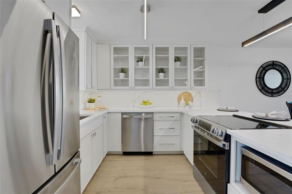 A modern kitchen features white cabinetry, stainless steel appliances, and a marble-patterned backsplash — 1100 S ORLANDO AVENUE UNIT 306, MAITLAND, FL