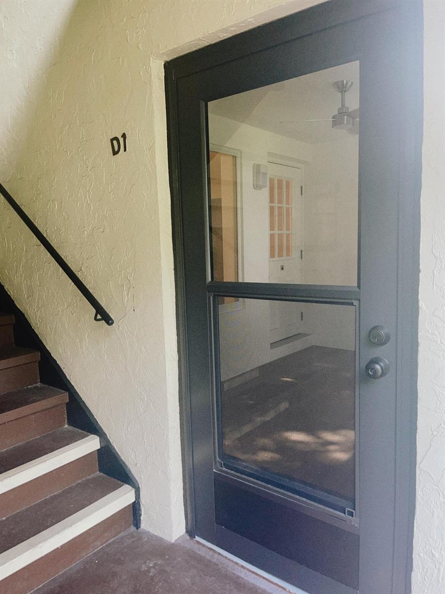 A dark-framed storm door leads to an entryway with stairs to the left — 5993 La Pinata Boulevard # D1, FL 33463, FL