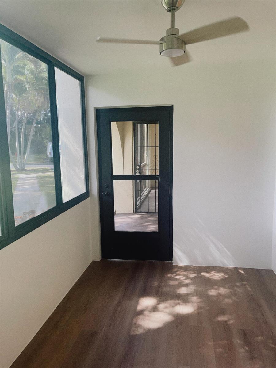 A sunroom with dark wood-look flooring, a ceiling fan, and a black-framed glass door — 5993 La Pinata Boulevard # D1, FL 33463, FL