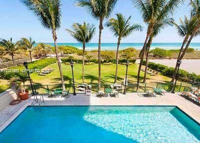 A swimming pool overlooks a grassy lawn, palm trees, and the ocean beyond — 9195 Collins Ave # 309, Surfside FL 33154, SURFSIDE, FL