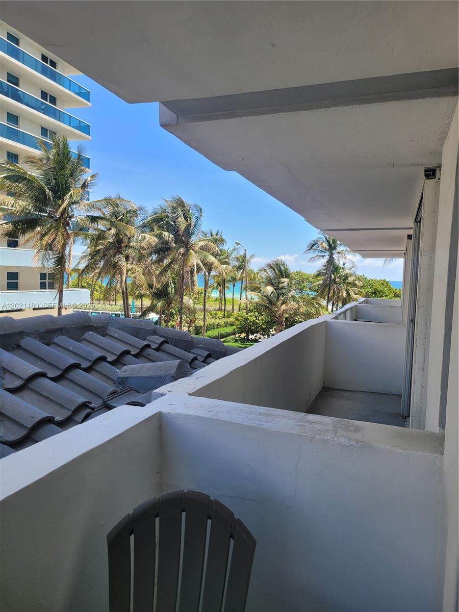A balcony with a concrete railing overlooks palm trees and the ocean — 9195 Collins Ave # 309, Surfside FL 33154, SURFSIDE, FL