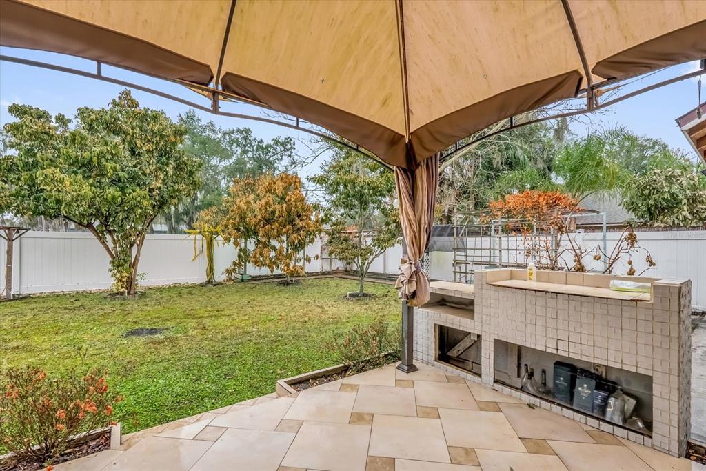 A tiled outdoor patio features a built-in grill station under a large tan gazebo canopy — 405 LATONIA STREET, KISSIMMEE, FL