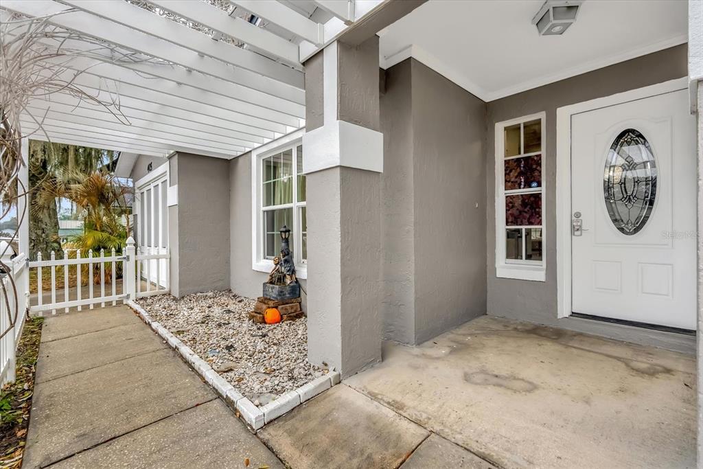 A covered front porch features a concrete walkway, a gravel garden bed, and a white door — 405 LATONIA STREET, KISSIMMEE, FL