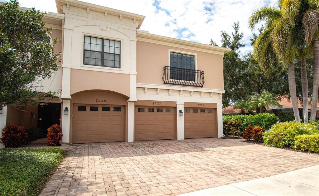 A two-story townhouse exterior features three garage doors and a paved driveway — 7231 HAMILTON ROAD, BRADENTON, FL