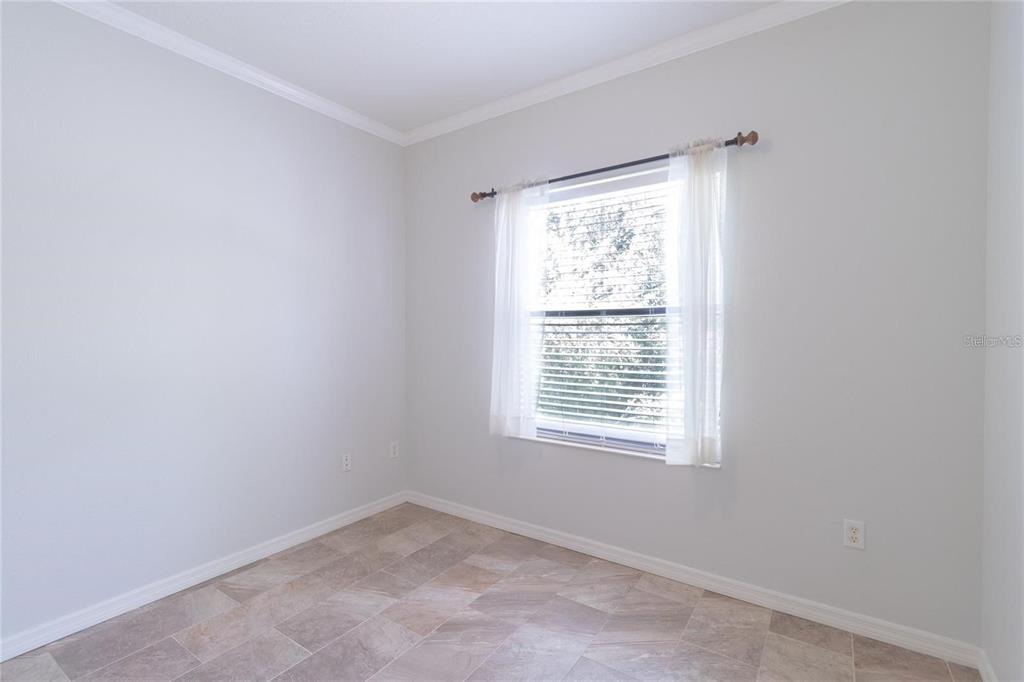 A room with light gray walls, tile flooring, and a window with white curtains — 7231 HAMILTON ROAD, BRADENTON, FL