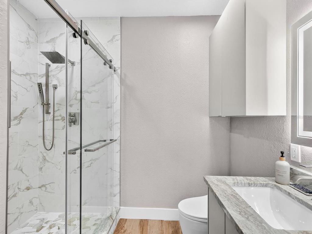 A bathroom features a glass-enclosed shower with marble-look tile, a vanity, and a toilet — 5000 CULBREATH KEY WAY UNIT 9-116, TAMPA, FL