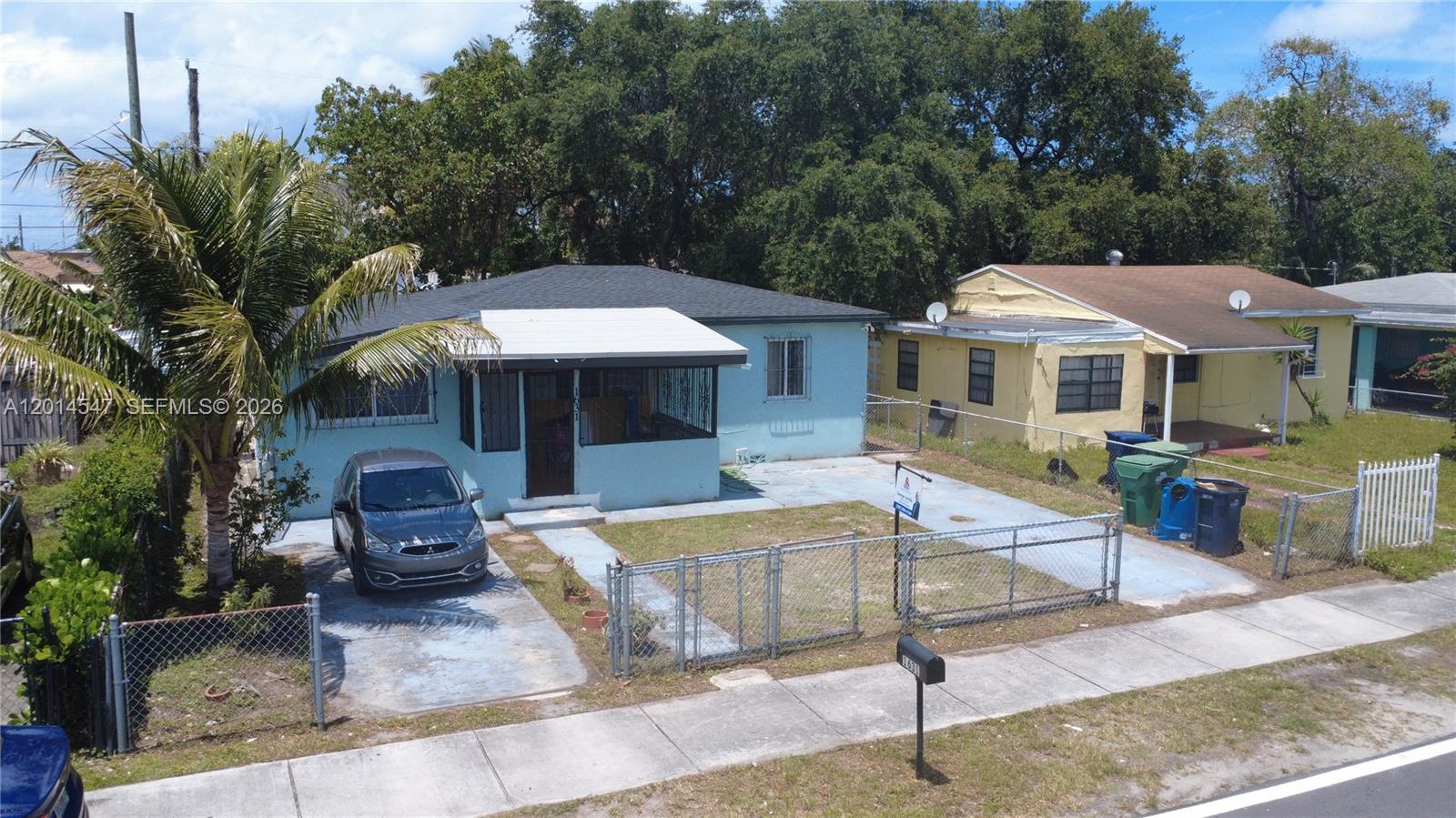 An aerial view shows a light blue house with a driveway and a fenced yard — 1631 NW 114th St, Miami FL 33167, MIAMI, FL