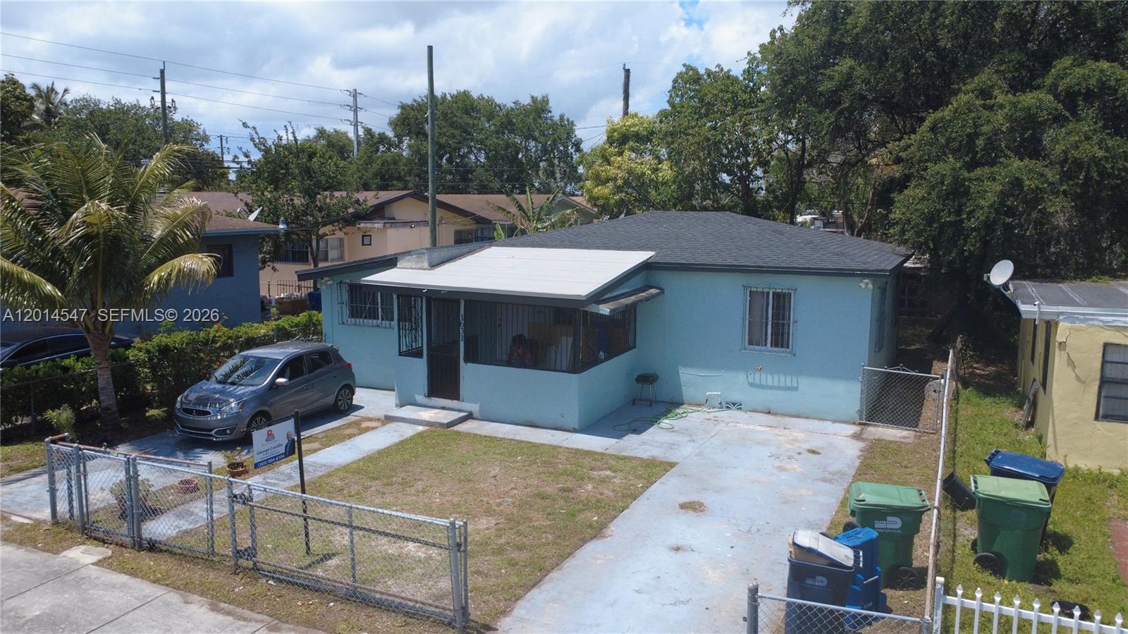 An aerial view shows a light blue house with a front porch and concrete driveway — 1631 NW 114th St, Miami FL 33167, MIAMI, FL