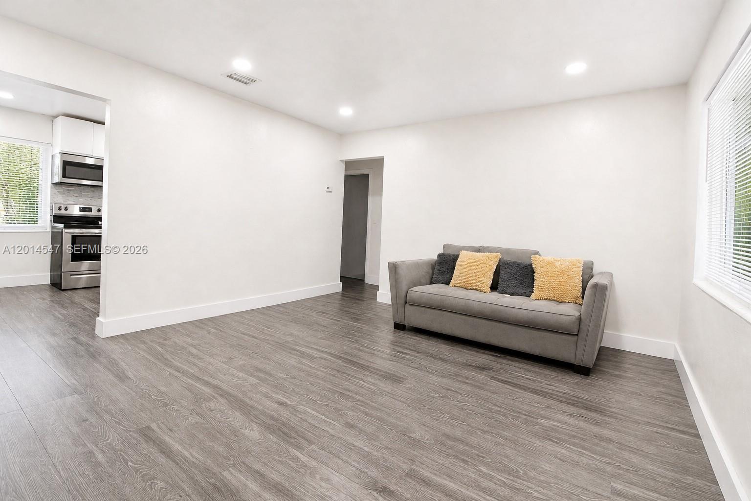 A living room features gray wood-look flooring, white walls, and a gray sofa — 1631 NW 114th St, Miami FL 33167, MIAMI, FL