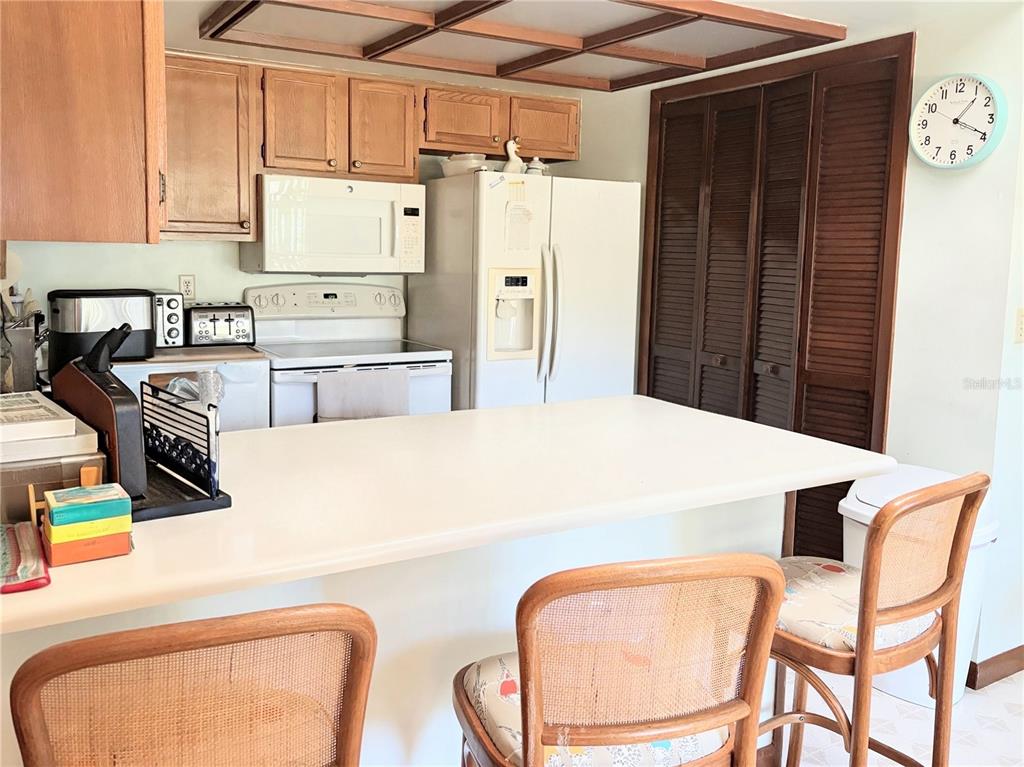 A kitchen features wood cabinets, white appliances, a breakfast bar, and two rattan chairs — 20235 MAJESTIC STREET, ORLANDO, FL