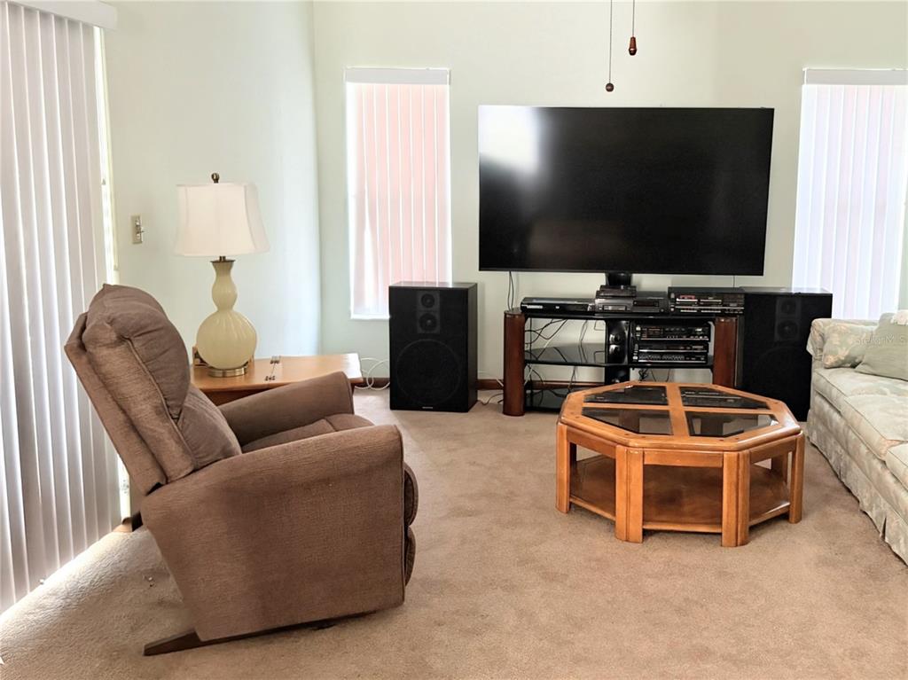 A living room features a large television, two speakers, a recliner, and a wooden coffee table — 20235 MAJESTIC STREET, ORLANDO, FL