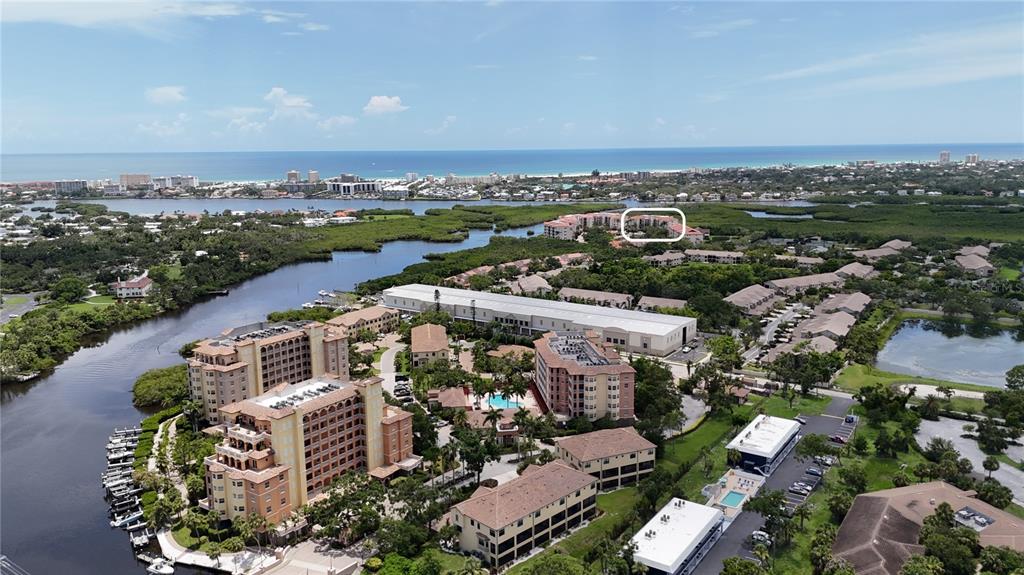 An aerial view shows a large resort complex with multiple buildings, pools, and surrounding greenery — 5420 EAGLES POINT CIRCLE UNIT 206, SARASOTA, FL