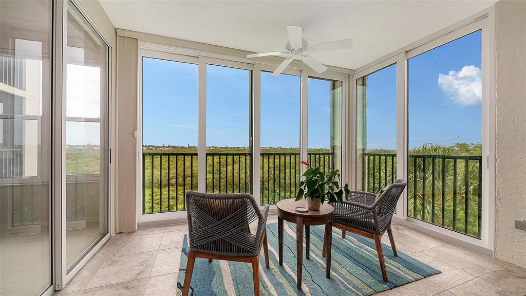 A sunroom features tile floors, a ceiling fan, and large windows overlooking a grassy landscape — 5420 EAGLES POINT CIRCLE UNIT 206, SARASOTA, FL