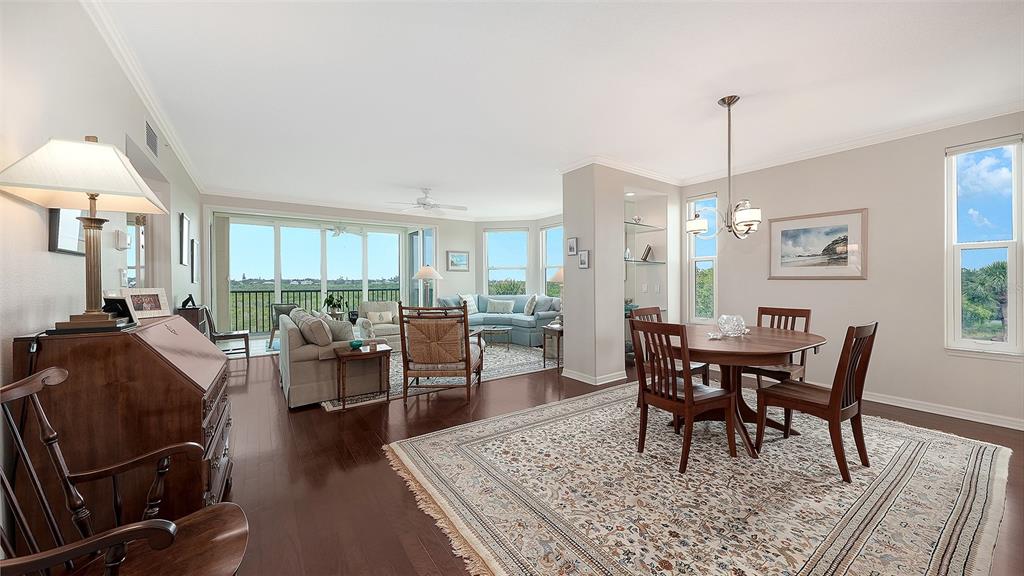 A dining area with a wooden table and chairs sits adjacent to a living room — 5420 EAGLES POINT CIRCLE UNIT 206, SARASOTA, FL